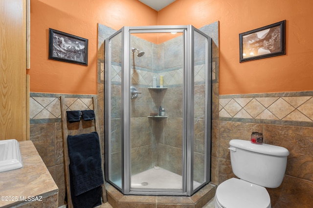 full bath featuring toilet, tile walls, a shower stall, and a wainscoted wall