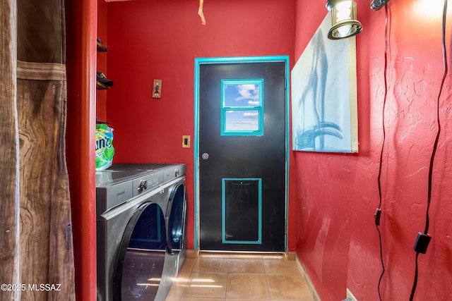 clothes washing area with washer and dryer, laundry area, baseboards, and tile patterned floors
