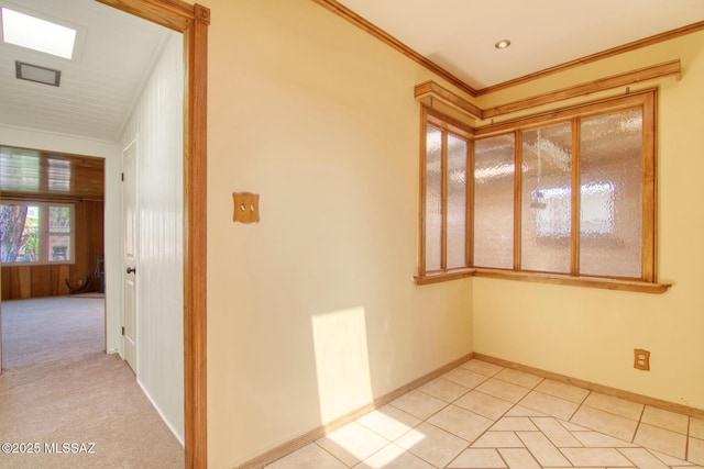 spare room with crown molding, light tile patterned floors, baseboards, and light carpet