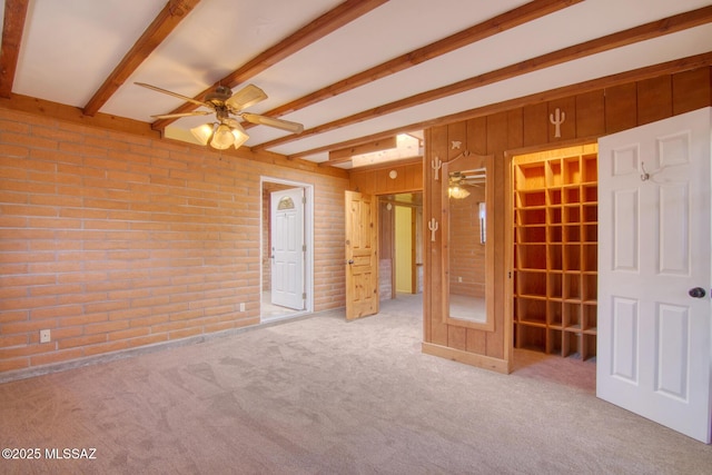 unfurnished bedroom with wooden walls, beam ceiling, brick wall, and carpet floors