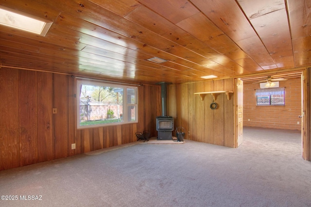 unfurnished room featuring carpet floors, wooden ceiling, wooden walls, and a wood stove