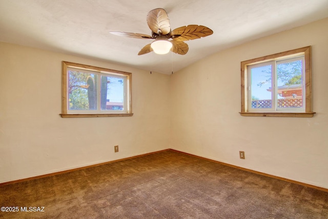 spare room featuring baseboards, ceiling fan, dark colored carpet, and plenty of natural light