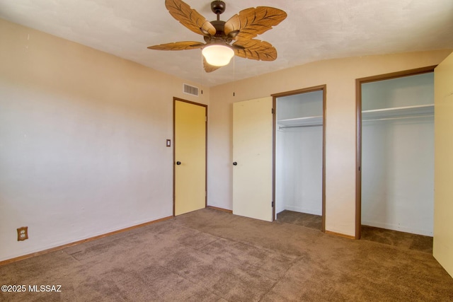 unfurnished bedroom featuring carpet, visible vents, multiple closets, and a ceiling fan