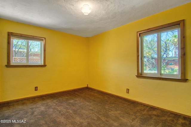 spare room with baseboards, dark colored carpet, a textured wall, and a textured ceiling