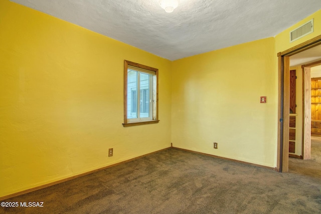 carpeted spare room featuring visible vents, baseboards, and a textured ceiling