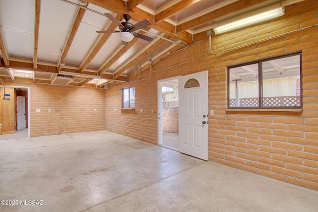 interior space with brick wall and a ceiling fan