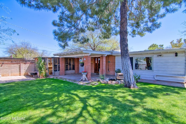 rear view of property featuring a patio, fence, and a lawn