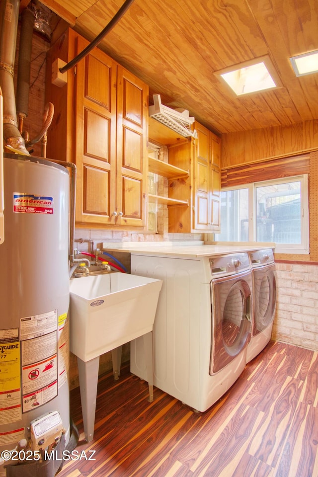 laundry room with laundry area, wood ceiling, wood finished floors, washing machine and clothes dryer, and gas water heater