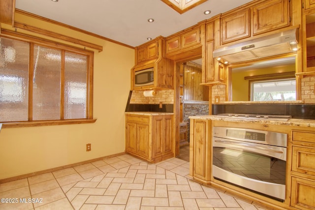 kitchen with under cabinet range hood, crown molding, brown cabinetry, stainless steel appliances, and decorative backsplash