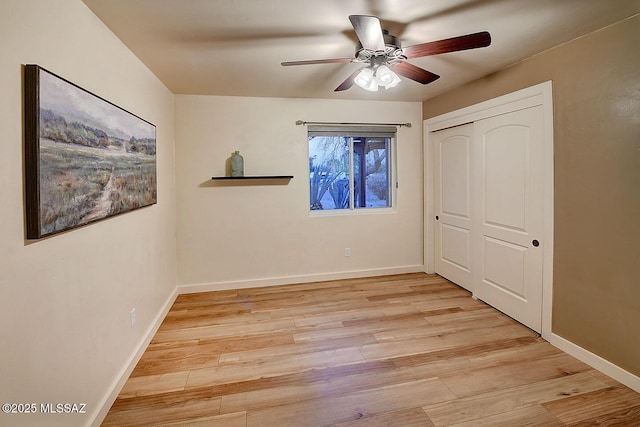 unfurnished bedroom with a closet, baseboards, light wood-type flooring, and a ceiling fan