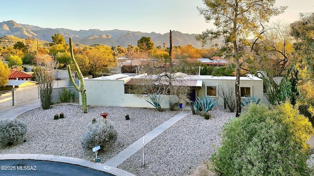 view of front of home featuring a fenced backyard, a mountain view, and stucco siding