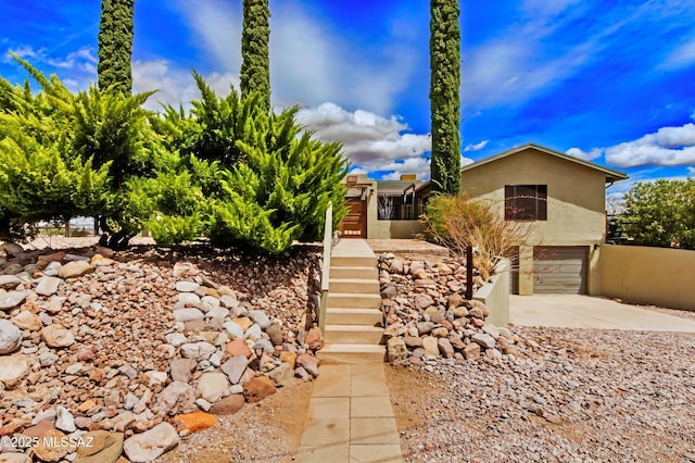 view of front facade featuring an attached garage, stucco siding, stairway, and concrete driveway