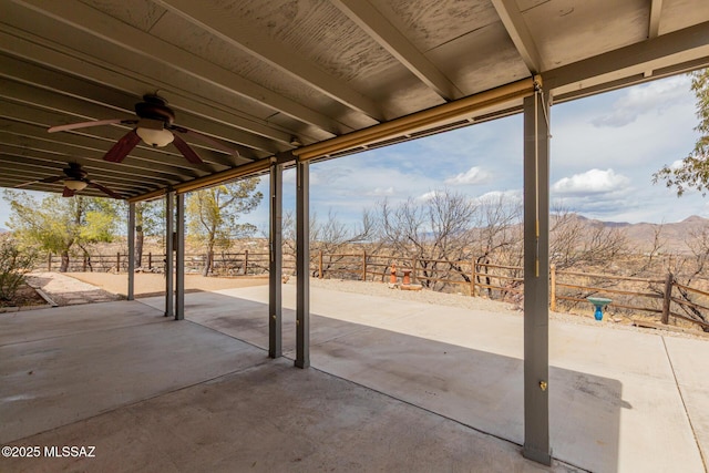 view of patio with a mountain view, fence, and ceiling fan