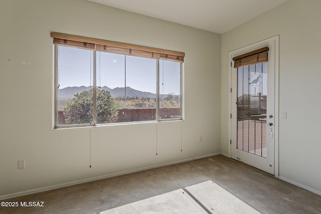 empty room with a mountain view, baseboards, and carpet