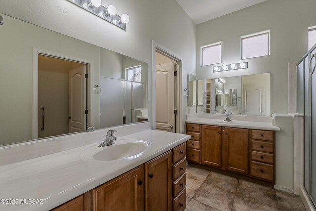 bathroom with a stall shower, two vanities, a sink, and a towering ceiling