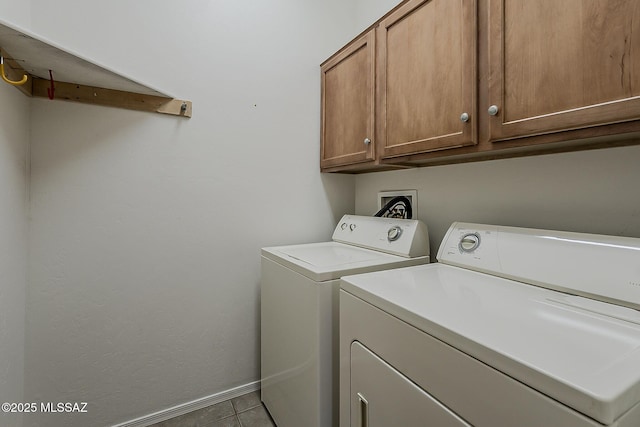 laundry area featuring cabinet space, tile patterned floors, washing machine and clothes dryer, and baseboards