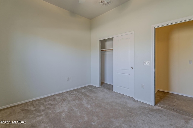 unfurnished bedroom with carpet, a closet, vaulted ceiling, visible vents, and baseboards