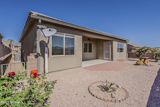 rear view of house with a patio, stucco siding, fence, and ceiling fan