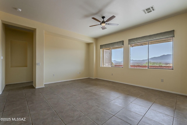 tiled spare room featuring visible vents, baseboards, and ceiling fan