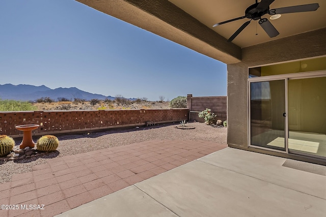 view of patio with a mountain view, a fenced backyard, and a ceiling fan