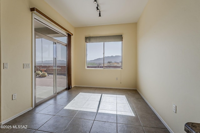 unfurnished room featuring track lighting, baseboards, and tile patterned flooring