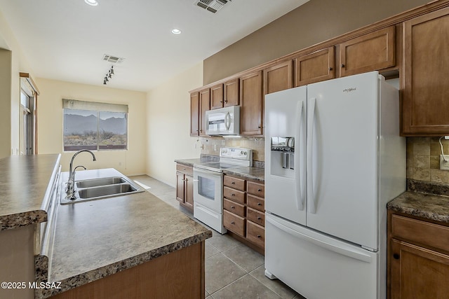 kitchen with visible vents, light tile patterned floors, a sink, white appliances, and decorative backsplash