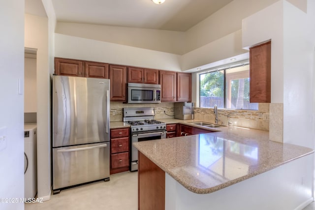 kitchen featuring decorative backsplash, a peninsula, stainless steel appliances, and a sink