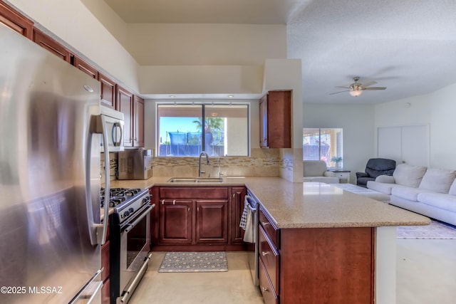 kitchen featuring a sink, decorative backsplash, open floor plan, stainless steel appliances, and a peninsula