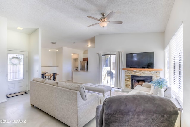 living area featuring lofted ceiling, a fireplace, a textured ceiling, and ceiling fan