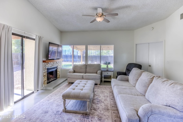 living area with ceiling fan, lofted ceiling, a healthy amount of sunlight, and a textured ceiling