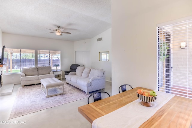 living area with vaulted ceiling, a ceiling fan, a textured ceiling, and visible vents