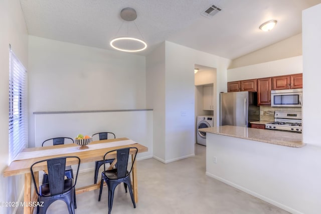 kitchen featuring visible vents, baseboards, a peninsula, appliances with stainless steel finishes, and washer / clothes dryer