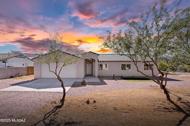 view of front of house featuring a tile roof, driveway, a garage, and stucco siding
