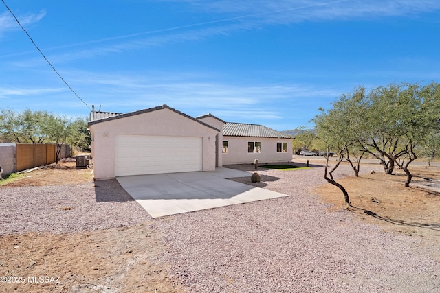 view of front facade with stucco siding, driveway, an attached garage, a tile roof, and fence