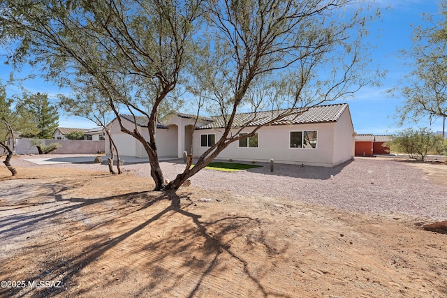 back of property featuring a tiled roof, a garage, stucco siding, fence, and concrete driveway
