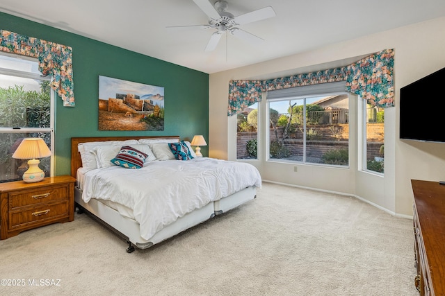 bedroom with a ceiling fan, light colored carpet, baseboards, and multiple windows