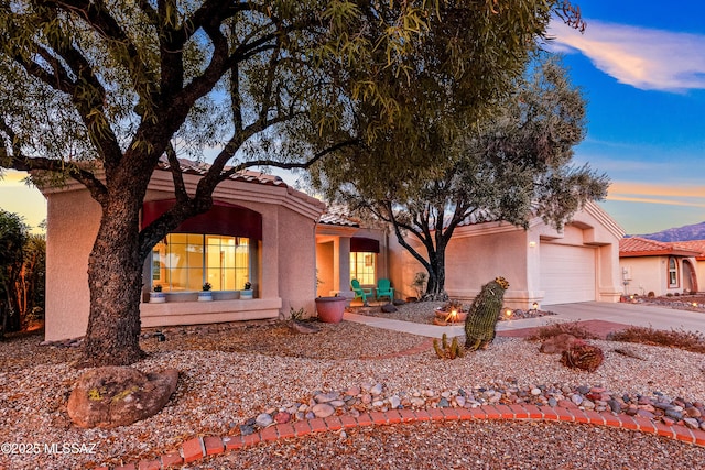 view of front of property featuring an attached garage, concrete driveway, stucco siding, and a tile roof