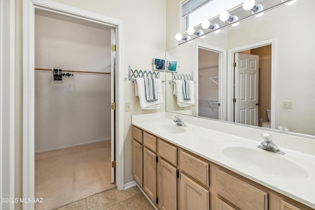 bathroom with toilet, double vanity, and a sink