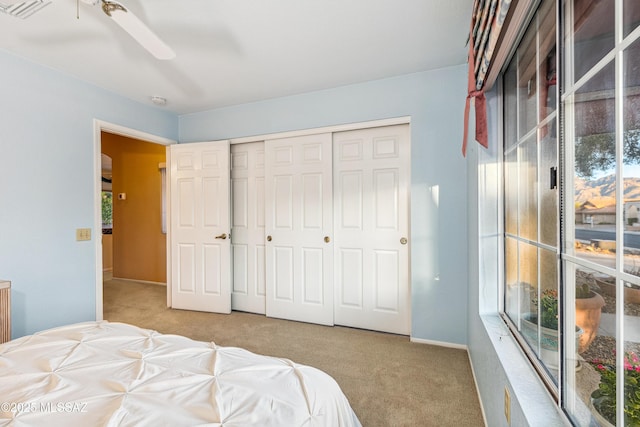 carpeted bedroom with a ceiling fan, a closet, multiple windows, and visible vents