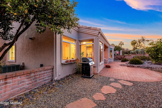 view of side of property featuring a patio, stucco siding, and cooling unit