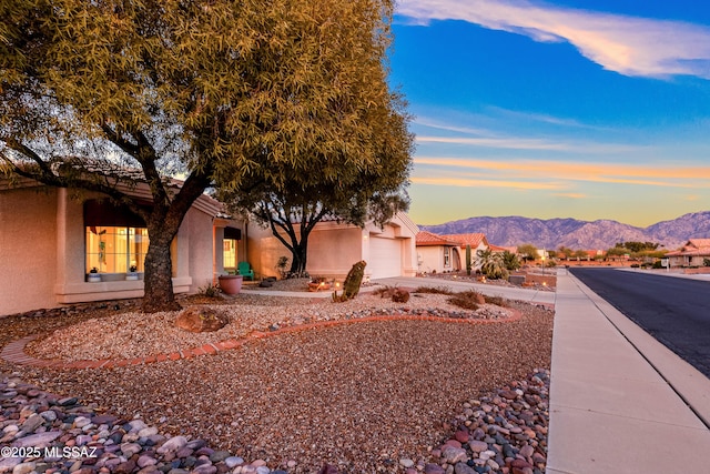 view of front of house with stucco siding, a tile roof, an attached garage, a mountain view, and driveway