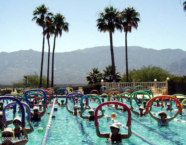 view of swimming pool with a mountain view and fence