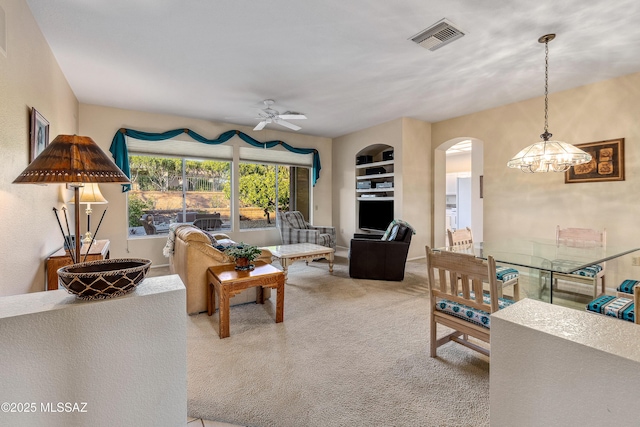 living area featuring arched walkways, visible vents, a ceiling fan, and carpet floors