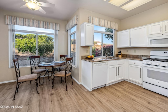 kitchen featuring a sink, light wood finished floors, white appliances, and white cabinetry