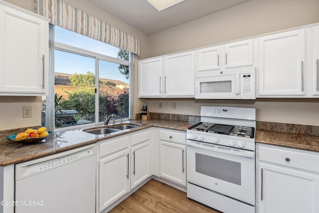 kitchen with white appliances, light wood-style floors, white cabinetry, and a sink