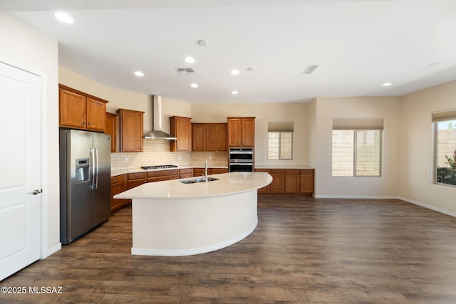 13906 N Rim Trl, Marana, AZ 85658 - kitchen with appliances with stainless steel finishes, wall chimney range hood, a sink, brown cabinetry, and a center island with sink