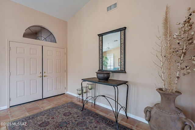 tiled entrance foyer featuring baseboards, vaulted ceiling, and visible vents
