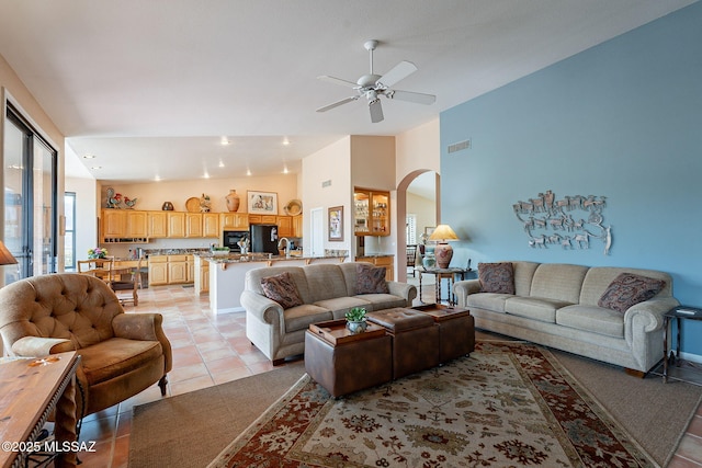 living room with arched walkways, a ceiling fan, visible vents, vaulted ceiling, and light tile patterned flooring