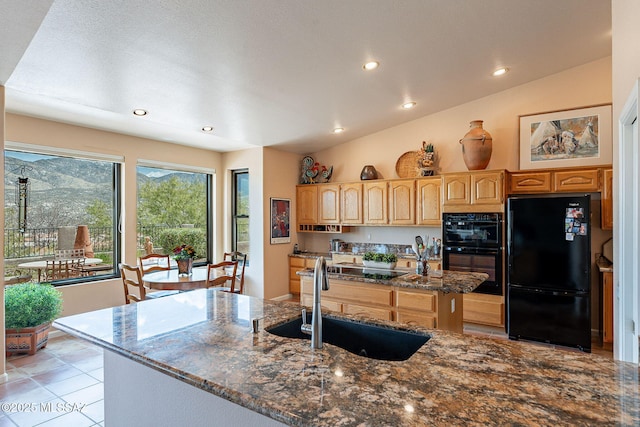 kitchen with light brown cabinetry, black appliances, a kitchen island, a sink, and lofted ceiling