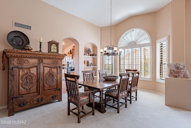 dining room featuring arched walkways, light colored carpet, a notable chandelier, and visible vents